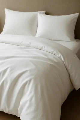 Net opgemaakt bed met wit Egyptisch katoenen dekbedovertrek en bijpassende kussens