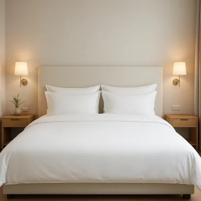 Hotelbed opgemaakt met wit dekbedovertrek en kussens, in een moderne en minimalistische slaapkamer